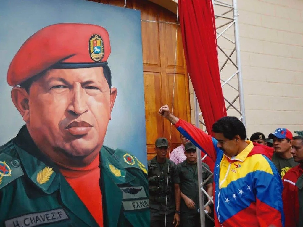 Maduro faz o clássico gesto comunista diante de um quadro do falecido Hugo Chávez
