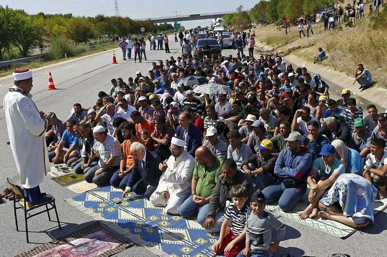 Imigrantes islâmicos praticando seu culto numa estrada da Eslovênia REUTERS/Osman Orsal
