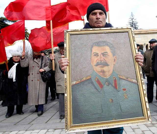 People carry red flags and a portrait of the late Soviet leader Josef Stalin during a ceremony to mark the 60th anniversary of his death in his hometown of Gori, about 80 km (50 miles) west of Georgia's capital Tbilisi March 5, 2013. REUTERS/David Mdzinarishvili (GEORGIA - Tags: POLITICS ANNIVERSARY SOCIETY)