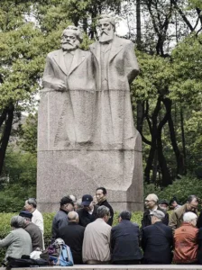 People chat in front of a statue of Karl Marx and Friedrich Engels at Fuxing Park in Shanghai, China, on Sunday, April 10, 2016. China's economy stabilized last quarter and gathered pace in March as a surge in new credit helped the property sector rebound while raising fresh question marks over the sustainability of the debt-fueled expansion. Photographer: Qilai Shen/Bloomberg