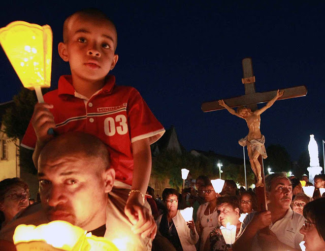Pilgrims attend a candlelight procession for the virgin Mary at the sanctuary of Lourdes, southwestern France, Sunday Aug. 14, 2016. Security measures for Lourdes' biggest annual event, the Feast of the Assumption, has been increased as France, on edge with fears of a new terror attack, continues to cancel festive and sports events for security reasons. (AP Photo/Bob Edme)