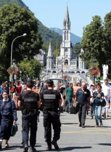 French police officers patrol near the site of the sanctuary in Lourdes, southwestern France, Sunday, Aug.14, 2016. Security measures for Lourdes' biggest annual event, the Feast of the Assumption, have been increased as France, on edge with fears of a new terror attack, continues to cancel festive and sports events for security reasons. (AP Photo/Bob Edme)