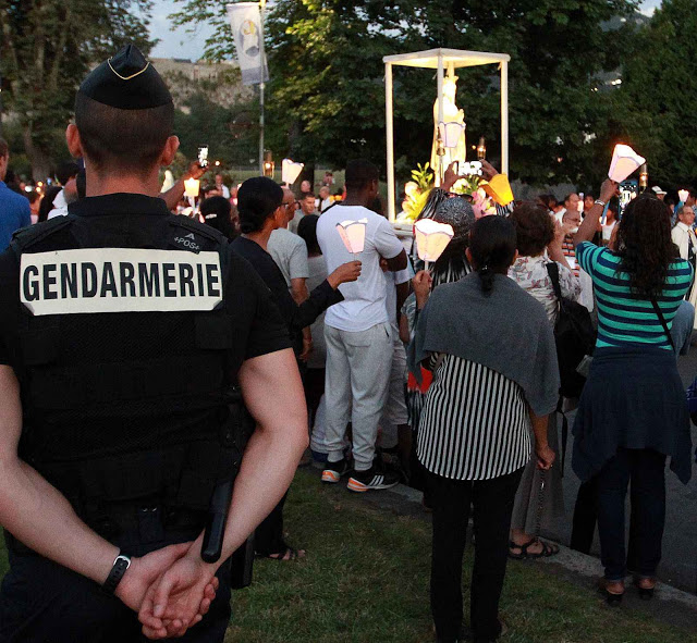 French police officers patrols in the site of the sanctuary in Lourdes, southwestern France, during a candlelight procession for the virgin Mary, Sunday Aug. 14, 2016. Security measures for Lourdes' biggest annual event, the Feast of the Assumption, has been increased as France, on edge with fears of a new terror attack, continues to cancel festive and sports events for security reasons. (AP Photo/Bob Edme)